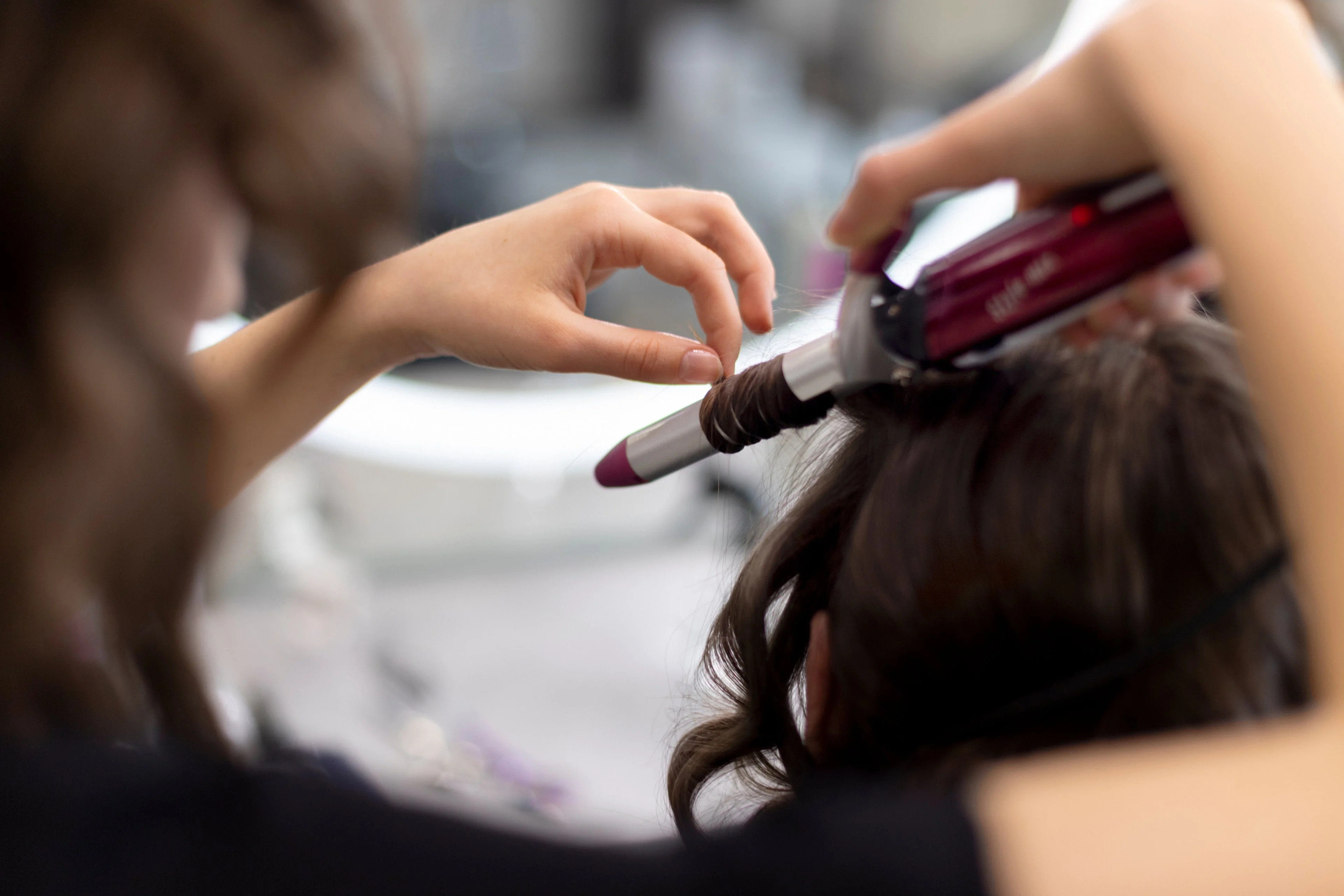 Hairdresser styling a client in the chair, mid-finish